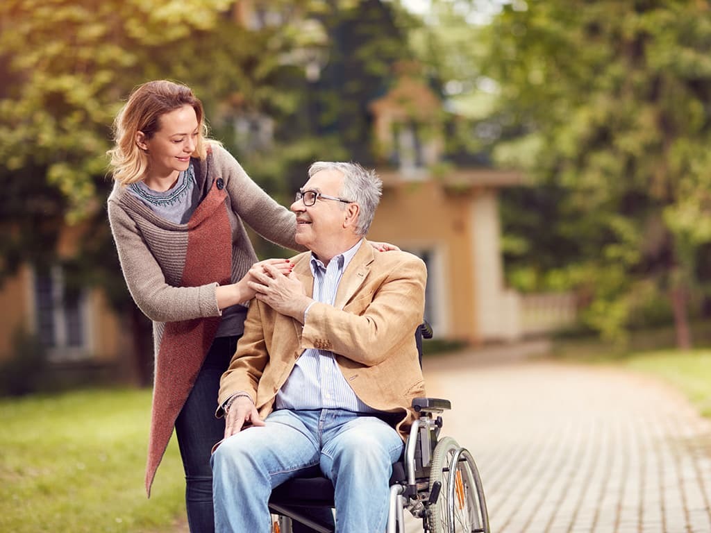 Caregiver smiling with family member in wheelchair